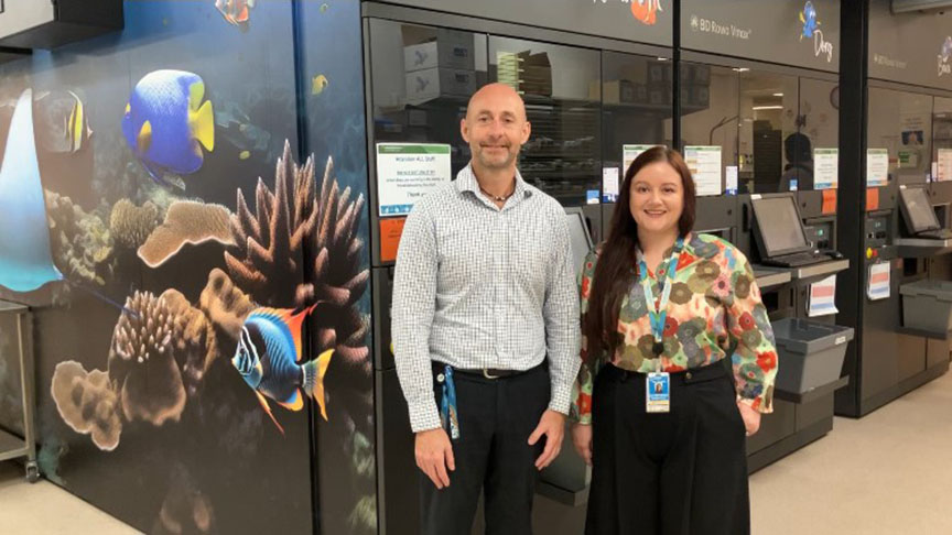 Staff members standing in front of pharmacy dispensing robot