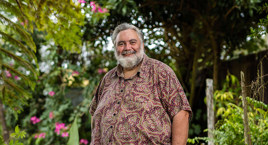 Indigenous man (Dr Louis Peachey) smiling and standing in front of garden